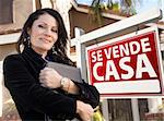 Proud, Attractive Hispanic Female Agent In Front of Spanish Se Vende Casa Real Estate Sign and House.