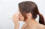 Young beautiful caucasian woman cleaning her face with cotton pad in the bathroom