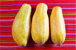 three papaya fruits on latin serape tablecloth  red background