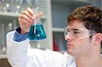 Young scientist looking at a liquid in an erlenmeyer in his laboratory