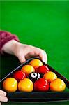 Close-up of a snooker player placing balls with triangle in a pool club
