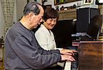 Senior couple having fun playing the piano