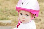 Cute toddler girl with pink helmet outdoors