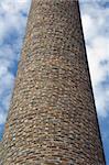 Weathered brick chimney of an old factory. Industrial architecture.