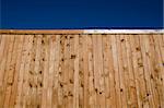 Image of a wooden fence shot from a low angle looking slightly up with blue sky