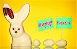 A spring composition of a white chocolate easter bunny and eggs over yellow background