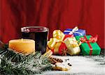 Lit candle with cookies, powder sugar, mulled wine and colorful gifts in the background (Selective Focus, Focus on candle)