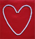 Heart from white pearls on an elegant red silk for St Valentine's day card