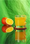 Fresh orange juice with oranges with reflection on green background (Selective Focus)