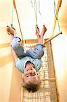 happy smiling 6 year old boy hanging on gymnastic rings