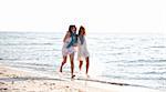 Two beautiful girls running on the beach.