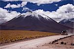 Car on the gravel road between volcanos in Chilean Atacama desert