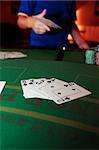 poker player throwing in cards with a straight flush of clubs in the foreground