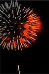 A burst of orange-red fireworks against a night sky.