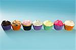 Cupcakes colorful cream muffin arrangement in a row line on turquoise