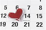 Heart shape glass paper weight on calendar page showing February 14 Valentine's Day