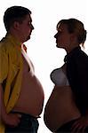 man and pregnant woman is standing face to face and showing their bellies and kissing, side view