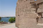 Egyptian hieroglyphic carvings on an outside wall at the Temple of Kom Ombo with view of River Nile