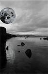 black and white night scenic view in kerry ireland of rocks and sea with mountains against a beautiful blue cloudy sky