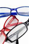 Three pairs of glasses with blue red and black frames on a white background