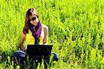 Young beautiful woman with laptop outdoor. Sunny summer day.
