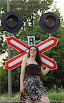 Young pretty girl near railroad's traffic sign. expression positive.