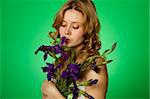 Happy close-up on a green background Happy young woman hugging a blue iris. Young Woman Hugging Flower