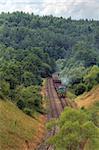 Freight train hauled by diesel locomotive passing the hilly forest