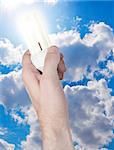 Glowing Energy Saving Bulb in Hand on Blue Sky Background