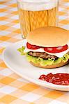 Mini cheese burger with tomato and lettuce on a white dish and a glass of beer.