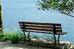 A solitary wooden bench facing the calm waters of a beautiful Alpine lake