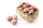 Garlic in a bright wicker basket with three heads apart; isolated on white.