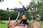 Two children playing on an old tractor