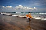 Man-surfer with board on a coastline. Bali. Indonesia