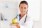 Doctor with stethoscope looking at an apple in the surgery