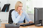 Working serious woman in front of a screen looking at it in an office