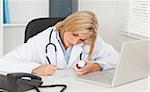 Doctor writing something down holding medicine in her office