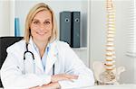 Smiling doctor with model spine next to her in her office