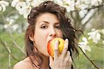 Beautiful young girl eating an apple in the park