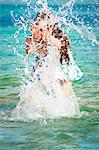 Beautiful young girl splashing the water in the sea