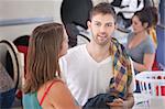 Handsome young Caucasian man with his girlfriend in laundromat