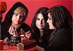 Three occult women with magic potion over red background