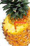 ripe pineapple cut on top with red straw