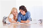 Smiling couple getting ready to move in a new house while lying on the floor