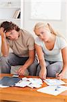 Despaired stressed couple calculating their expenses in the living room