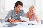 Worn out couple listing expenses in the living room