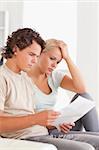 Shocked couple reading letters in the living room