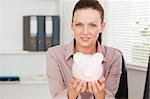 A businesswoman is holding a piggy bank in her office