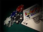 Red, blue, white, black poker chips on a green felt gaming table. Two cards and chips are spotlighted.  Jack of Spades and Ace of Spades gives a Blackjack winner.