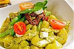 fresh lumaconi pasta and pesto sauce with vegetables and sun dried tomatoes,typical italian food